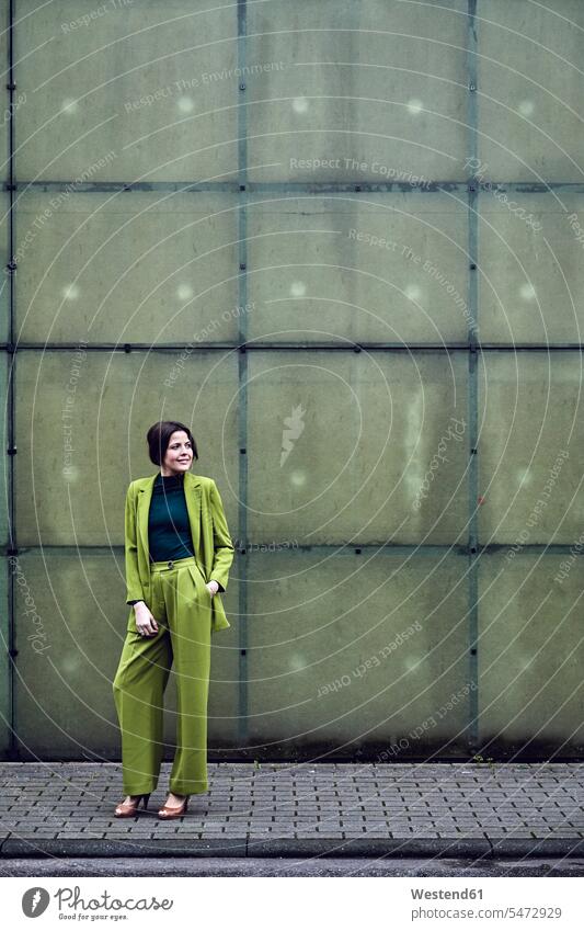 Elegante Geschäftsfrau in grünem Anzug steht an einer Wand Job Berufe Berufstätigkeit Beschäftigung Jobs geschäftlich Geschäftsleben Geschäftswelt