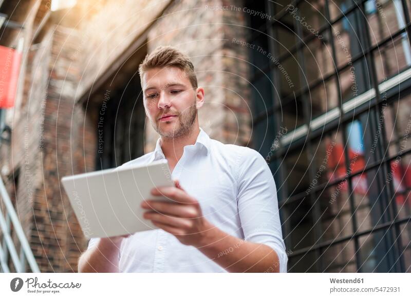 Junger Geschäftsmann mit Tablette in einem Backsteingebäude Job Berufe Berufstätigkeit Beschäftigung Jobs geschäftlich Geschäftsleben Geschäftswelt