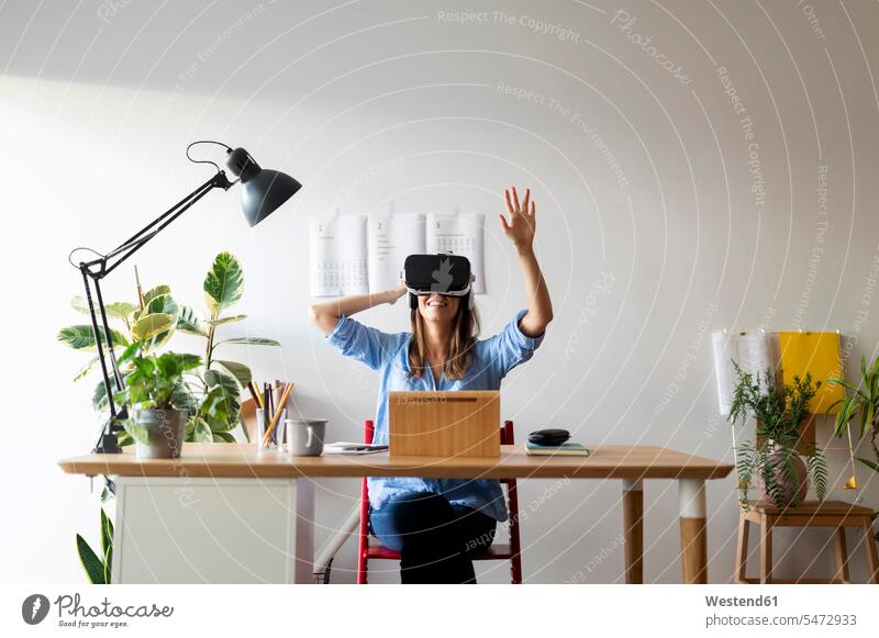 Junge Frau schaut durch einen Virtual-Reality-Simulator, während sie am Schreibtisch im Home-Office sitzt Farbaufnahme Farbe Farbfoto Farbphoto Spanien