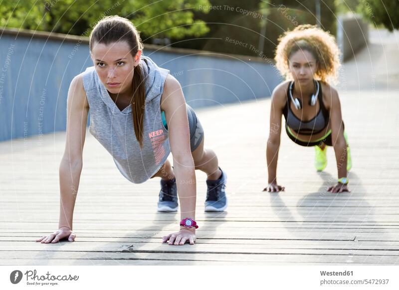 Zwei sportliche junge Frauen machen Liegestütze auf einer Brücke Leute Menschen People Person Personen Europäisch Kaukasier kaukasisch 2 2 Menschen 2 Personen