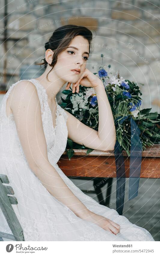 Nachdenkliche junge Frau im Hochzeitskleid sitzt am Tisch Brautkleid weiblich Frauen nachdenklich sitzen sitzend Tische Erwachsener erwachsen Mensch Menschen
