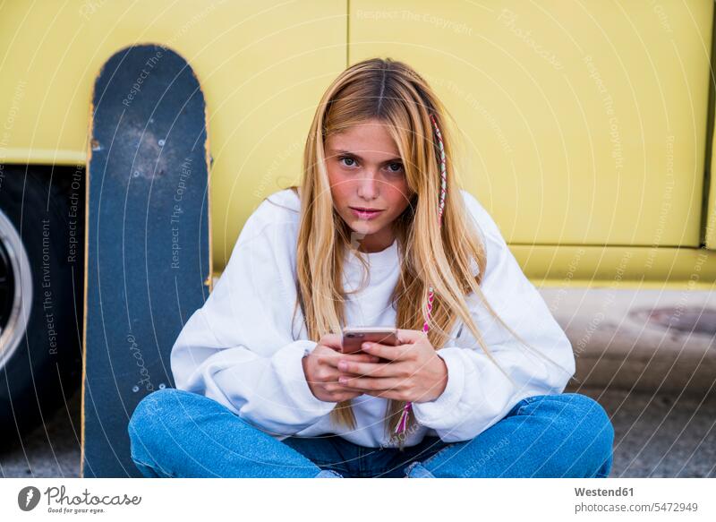 Junge Frau mit Skateboard und Handy sitzt in einem Lieferwagen Portrait Porträts Portraits Rollbretter Skateboards Mobiltelefon Handies Handys Mobiltelefone