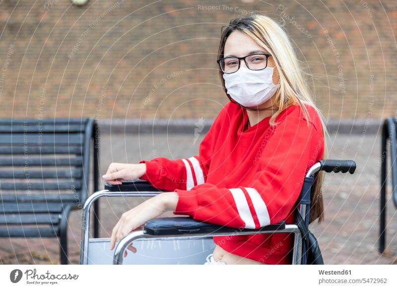 Behinderte Frau im Rollstuhl mit Gesichtsmaske während des Coronavirus-Ausbruchs Farbaufnahme Farbe Farbfoto Farbphoto Außenaufnahme außen draußen im Freien Tag