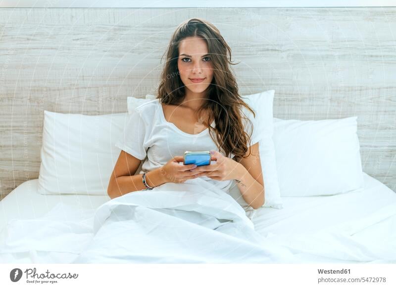 Porträt der jungen Frau mit Handy im Bett zu Hause Leute Menschen People Person Personen Europäisch Kaukasier kaukasisch 1 Ein ein Mensch eine nur eine Person