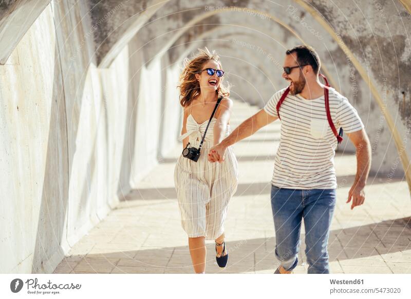 Spanien, Andalusien, Malaga, sorgloses Touristenpaar läuft unter einem Torbogen in der Stadt staedtisch städtisch rennen Durchgang Paar Pärchen Paare