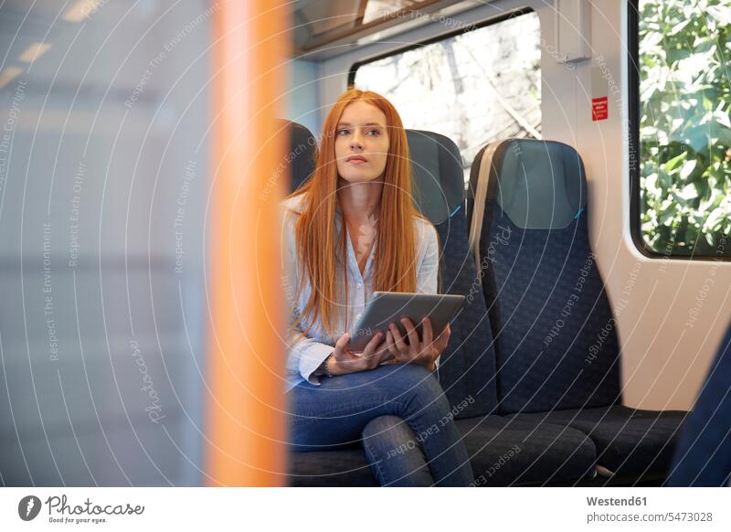 Nachdenkliche junge Frau hält digitales Tablett in der Hand, während sie im Zug sitzt Farbaufnahme Farbe Farbfoto Farbphoto Zuginnenraum Bahn Züge Bahnen