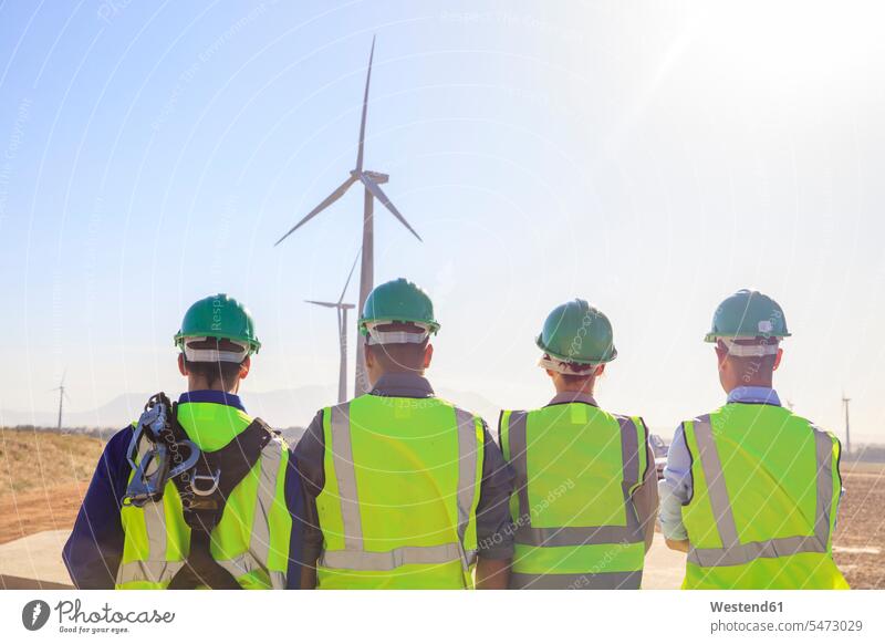 Rückansicht von vier Ingenieuren auf einem Windpark Technik Techniken Technologie Windenergieanlage WEA WEAs Windkraftwerk Windenergieanlagen Windkraftwerke