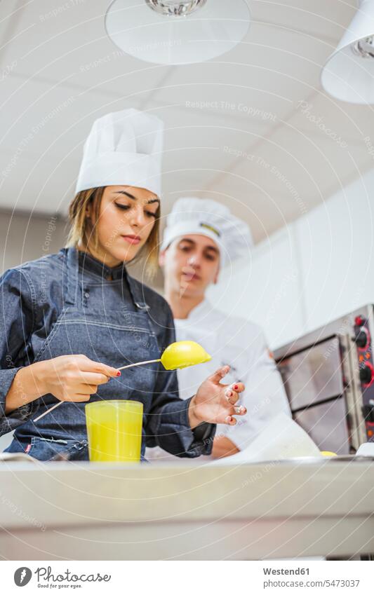 Nachwuchs-Köche bereiten ein Dessert zu Europäer zwei Personen junger Mann 25-30 Jahre junge Frau Kochhaube kochen Restaurant Küche Können zubereiten