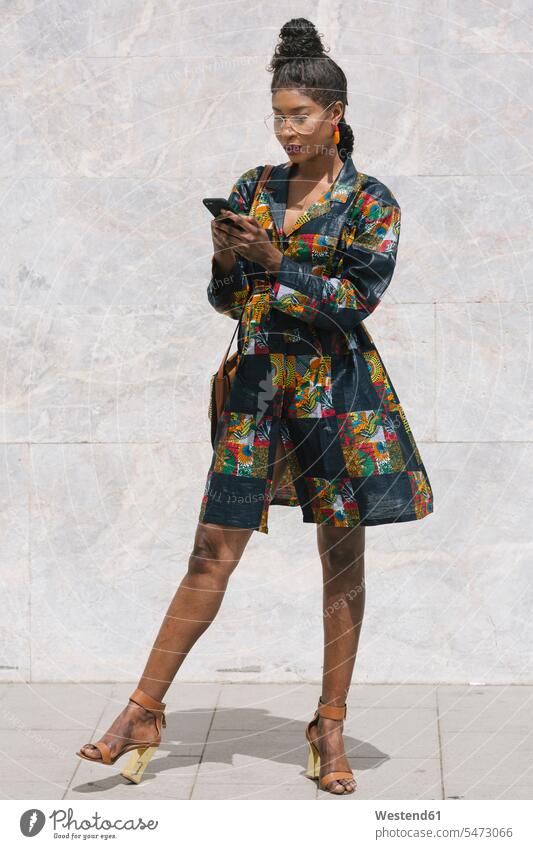 Porträt einer schicken Frau in einem gemusterten Kleid, die ein Mobiltelefon benutzt Informationen Kleider Telekommunikation telefonieren Handies Handys