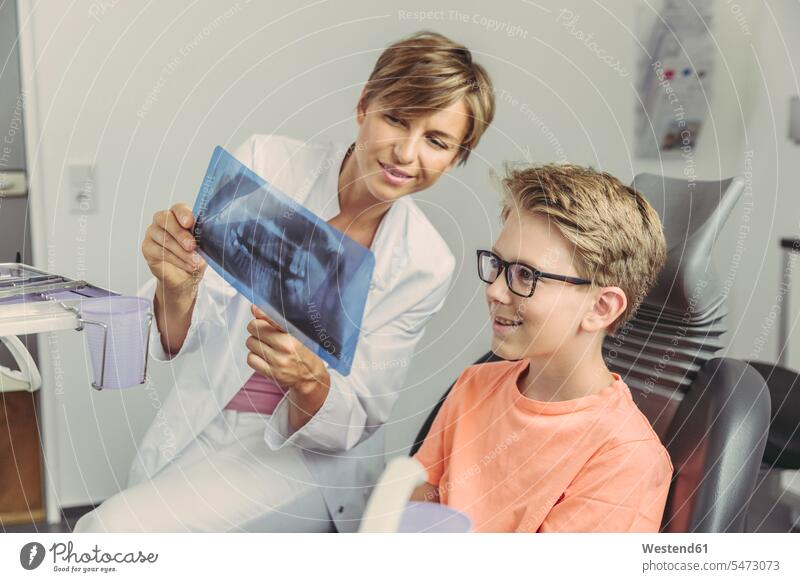 Weibliche Zahnärztin erklärt Junge ein Röntgenbild Buben Knabe Jungen Knaben männlich Roentgenbild Roentgenbilder Röntgenbilder zeigen vorführen präsentieren