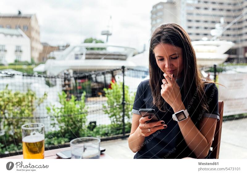 Junge schöne Frau mit ihrem Smartphone auf einer Terrasse weiblich Frauen Terrassen Handy Mobiltelefon Handies Handys Mobiltelefone Erwachsener erwachsen Mensch