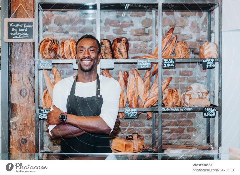 Lächelnder Mann bei der Arbeit in einer Bäckerei Job Berufe Berufstätigkeit Beschäftigung Jobs handeln Verkaeufer Schilder Zeichen Ablage Regale Kauf freuen