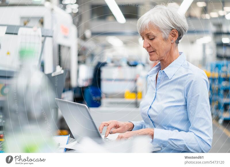 Ältere Geschäftsfrau mit Laptop in einer Fabrik Notebook Laptops Notebooks Fabriken Geschäftsfrauen Businesswomen Businessfrauen Businesswoman Computer Rechner