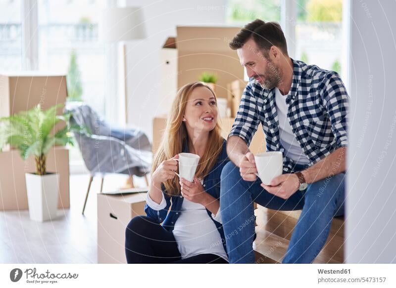 Mann und schwangere Frau ziehen in eine neue Wohnung und machen eine Kaffeepause Pause wohnen Wohnungen einziehen Einzug Paar Pärchen Paare Partnerschaft