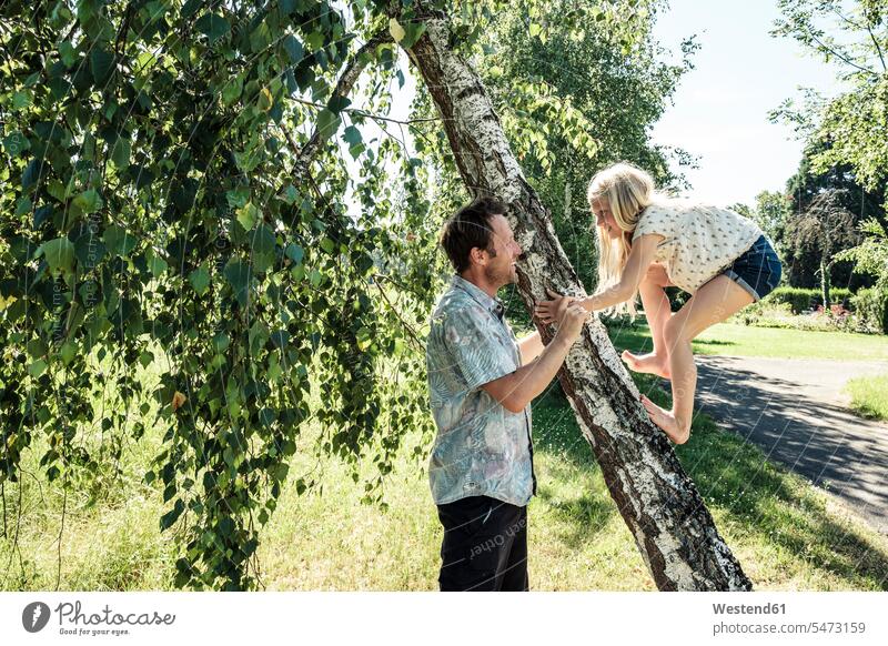 Vater hilft Tochter beim Klettern auf einen Birkenstamm im Park steigen Jahreszeiten Frühjahr Lenz sommerlich Sommerzeit freuen Frohsinn Fröhlichkeit Heiterkeit