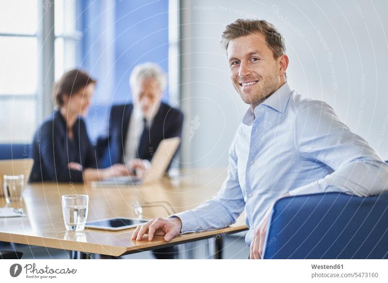 Porträt eines lächelnden Geschäftsmannes während einer Sitzung im Amt Leute Menschen People Person Personen Europäisch Kaukasier kaukasisch Gruppe von Menschen