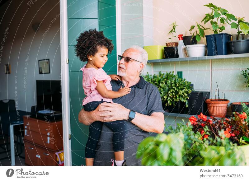 Großvater trägt eine Sonnenbrille und trägt seine Enkelin auf dem Balkon Farbaufnahme Farbe Farbfoto Farbphoto Freizeitbeschäftigung Muße Zeit Zeit haben