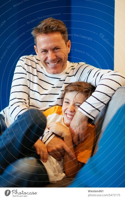 Glücklicher Vater kitzelt Sohn zu Hause auf der Couch Sofa Couches Liege Sofas Zuhause daheim glücklich glücklich sein glücklichsein Papas Väter Vati Vatis