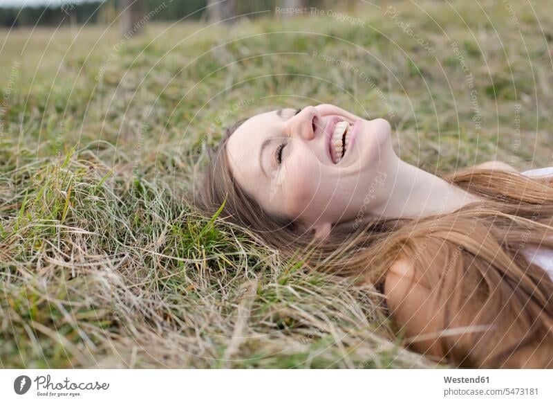 Lachende junge Frau auf einer Wiese liegend weiblich Frauen Wiesen lachen liegt Erwachsener erwachsen Mensch Menschen Leute People Personen positiv Emotion