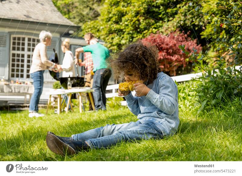 Junge isst einen Maiskolben auf einem Familiengrill im Garten Generation Leute Menschen People Person Personen Mehr Generationen Familien