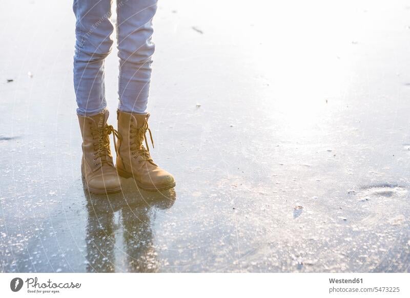 Deutschland, Brandenburg, Straussee, Füße mit Stiefeln auf gefrorenem See Winterbekleidung Winterkleidung warme Kleidung Freizeit Muße gefrorener See