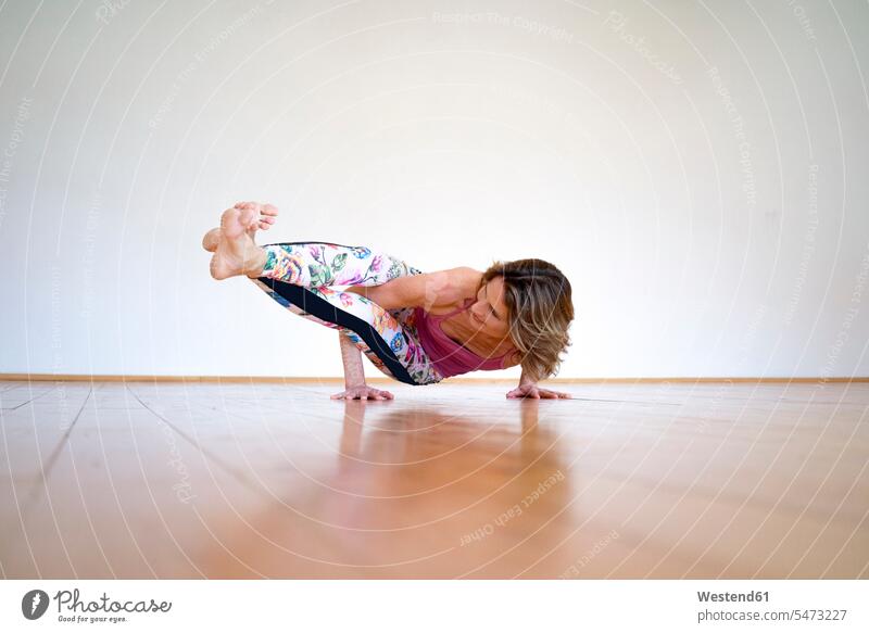 Reife Frau praktiziert Yoga auf dem Boden im leeren Raum Böden Boeden üben ausüben Übung trainieren Zimmer Räume weiblich Frauen Erwachsener erwachsen Mensch