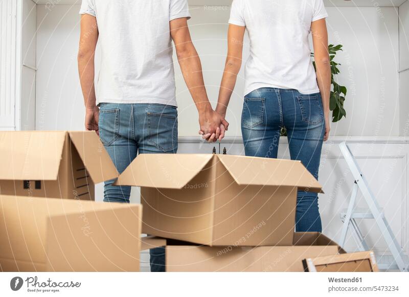 Nahaufnahme eines Paares mit Pappkartons, die Hand in Hand im neuen Haus stehen Karton Kartons Wohnung Mietwohnungen wohnen Zuhause zu Hause daheim stehend