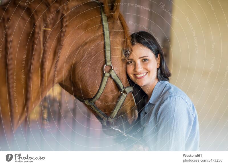 Porträt einer lächelnden Frau mit einem Pferd auf einem Bauernhof weiblich Frauen Equus caballus Pferde Portrait Porträts Portraits Fürsorge kümmern fürsorglich