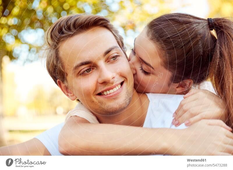 Glückliches junges Paar in der Liebe küssen in einem Park Küsse Kuss Pärchen Paare Partnerschaft Parkanlagen Parks verliebt glücklich glücklich sein