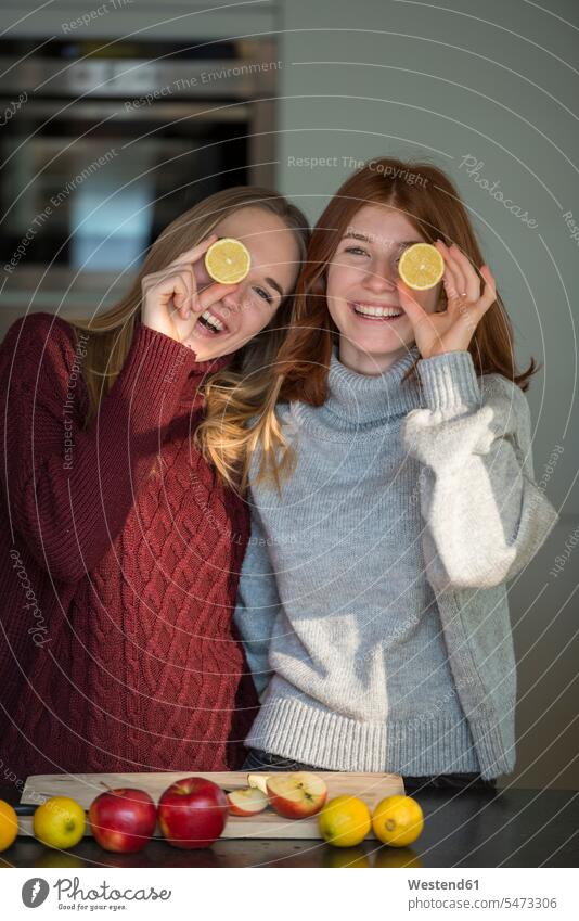 Zwei lachende Freunde halten sich Zitronenhälften vor die Augen Freundinnen Hälfte halbe halbiert halber Haelfte Freundschaft Kameradschaft Querschnitt