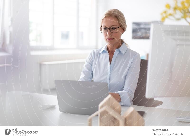 Geschäftsfrau arbeitet über Laptop auf dem Schreibtisch im Heimbüro Farbaufnahme Farbe Farbfoto Farbphoto Deutschland Innenaufnahme Innenaufnahmen innen drinnen