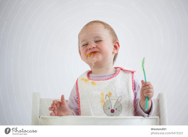 Porträt von lächelnden Baby Mädchen auf Hochstuhl Essen Brei Kinderstuhl Kinderstühle Kinderstuehle Babystuhl essen essend weibliche Babys weibliches Baby