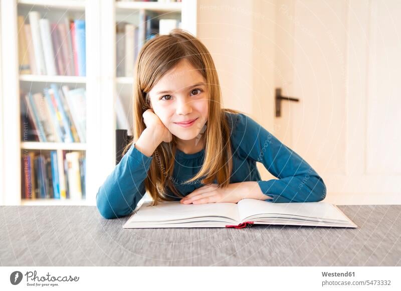 Mädchen liest ein Buch lächeln Freude Leseratte lesen lernen Bildung Kind Mensch Freizeit Wohnzimmer glücklich Schulbuch Zuversicht Interesse Europäer