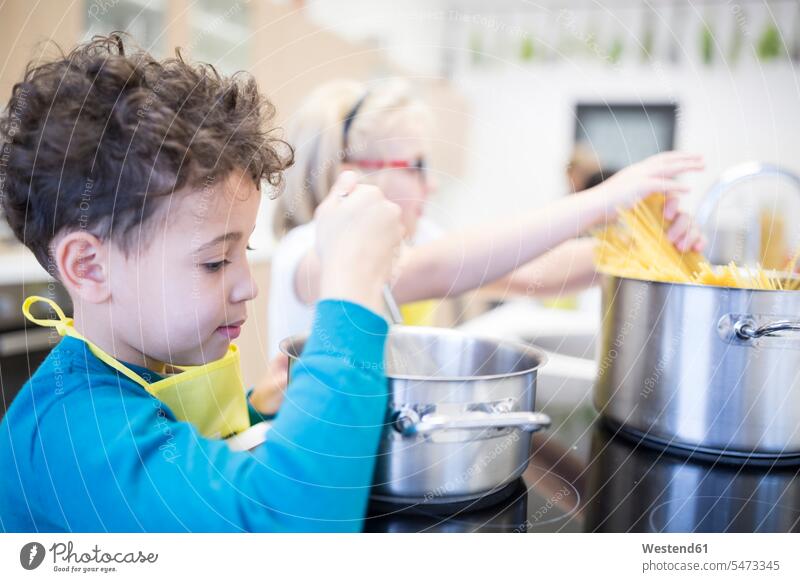 Schülerinnen und Schüler bei der Zubereitung von Nudeln im Kochkurs zubereiten kochen Essen zubereiten Schule Schulen Pasta Schulkind Schueler Schulkinder