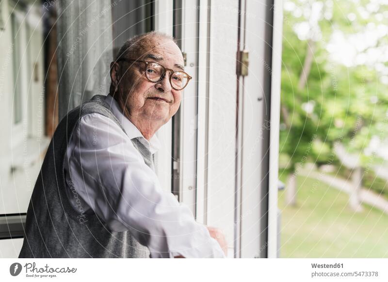 Porträt eines lächelnden älteren Mannes am offenen Fenster stehend Leute Menschen People Person Personen Alleinstehende Alleinstehender Singles Unverheiratete