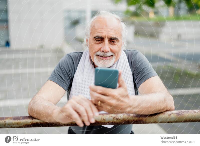 Nahaufnahme eines älteren Mannes, der ein Smartphone benutzt, während er am Geländer steht Farbaufnahme Farbe Farbfoto Farbphoto Außenaufnahme außen draußen