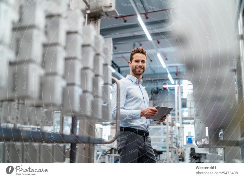 Porträt eines lächelnden Geschäftsmannes mit Tablette in einer modernen Fabrik Job Berufe Berufstätigkeit Beschäftigung Jobs geschäftlich Geschäftsleben