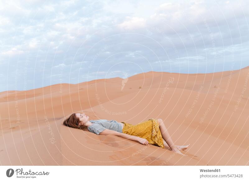Junge Frau liegt in einer Sanddüne in der Wüste Sahara, Merzouga, Marokko abends allein liegend Erlebnisse Muße Friede friedlich Individuell auf Achse