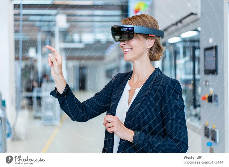 Lächelnde Geschäftsfrau mit AR-Brille in einer modernen Fabrik Job Berufe Berufstätigkeit Beschäftigung Jobs geschäftlich Geschäftsleben Geschäftswelt