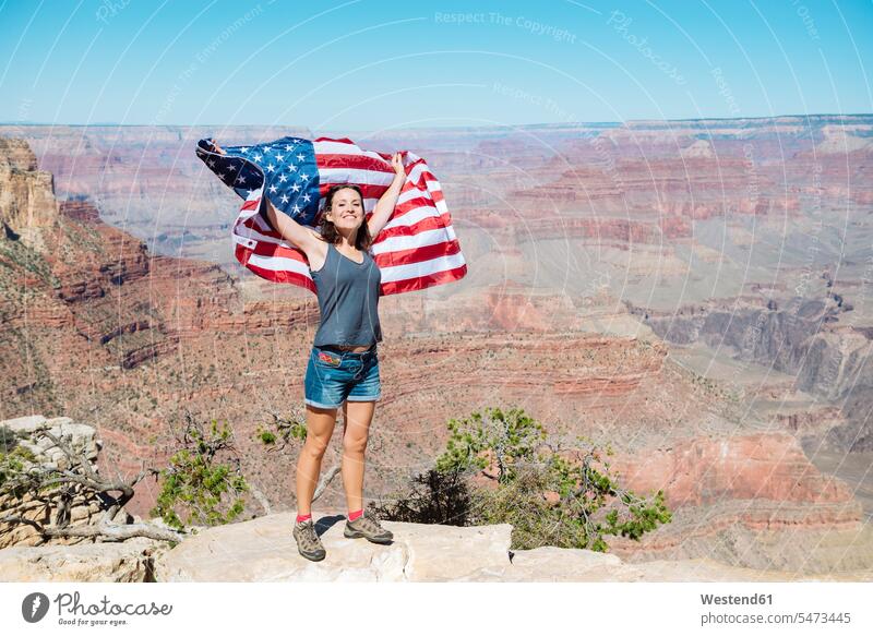 USA, Arizona, lächelnde Frau mit amerikanischer Flagge im Grand Canyon National Park Fahnen Flaggen weiblich Frauen Nationalpark Nationalparks Nationalflagge