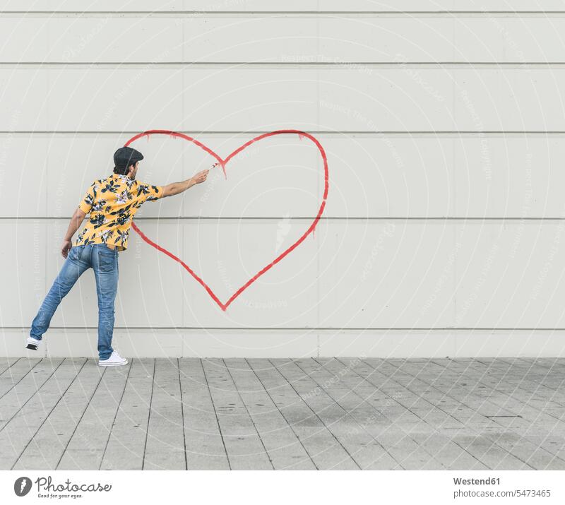 Digitales Komposit eines jungen Mannes, der ein Herz an eine Wand zeichnet Leute Menschen People Person Personen Europäisch Kaukasier kaukasisch 1 Ein