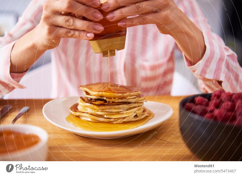 Junge Frau mit süßen Pfannkuchen zum Frühstück, Nahaufnahme junge Frau junge Frauen frühstücken Zuhause zu Hause daheim Pancake Eierkuchen Pancakes weiblich