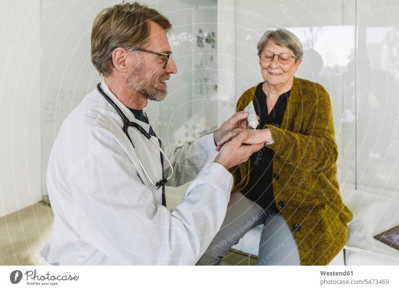 Arzt legt Salbe auf die Hand eines älteren Patienten Gesundheit Gesundheitswesen medizinisch Erkrankung Erkrankungen Krankheiten Kranke Kranker Job Berufe