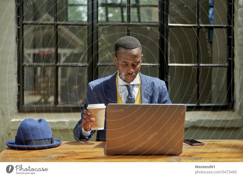 Modischer junger Geschäftsmann im altmodischen Anzug mit Laptop in einem Café im Freien geschäftlich Geschäftsleben Geschäftswelt Geschäftsperson