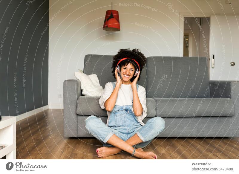 Glückliche Frau sitzt zu Hause mit Kopfhörern Zuhause daheim lächeln sitzen sitzend weiblich Frauen Kopfhoerer Erwachsener erwachsen Mensch Menschen Leute
