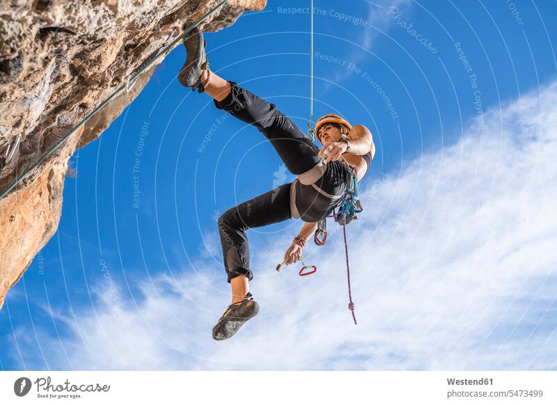 Weibliche Bergsteigerin seilt sich von Felswand ab Helme steigen Muße Courage mutig Tapferkeit geschützt schützen Absicherung trainieren auf Achse in Bewegung