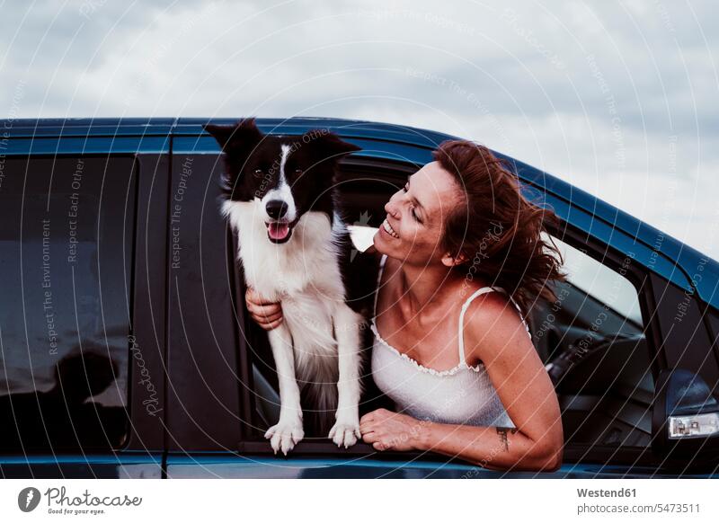 Lächelnde Frau sieht Hund an, während sie sich durch das Autofenster lehnt Farbaufnahme Farbe Farbfoto Farbphoto Spanien Freizeitbeschäftigung Muße Zeit