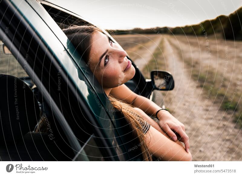 Lächelnde junge Frau lehnt sich aus dem Autofenster Fenster weiblich Frauen lächeln Wagen PKWs Automobil Autos Erwachsener erwachsen Mensch Menschen Leute