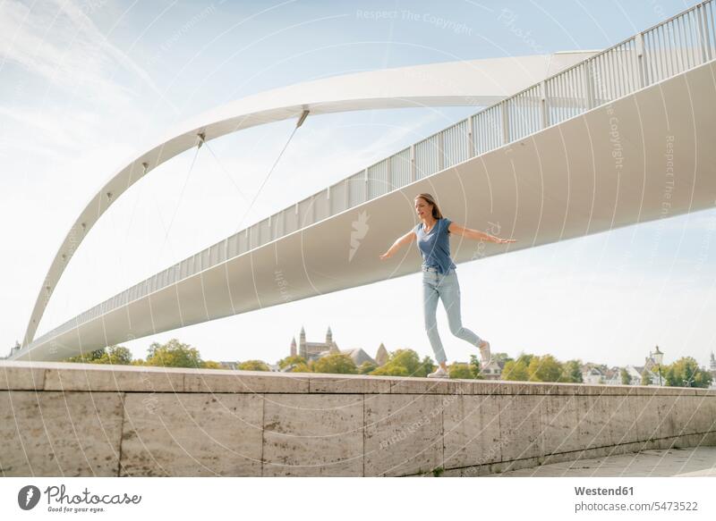Niederlande, Maastricht, junge Frau balanciert auf einer Mauer an einer Brücke balancieren Balance Mauern Bruecken Brücken weiblich Frauen ausgeglichen