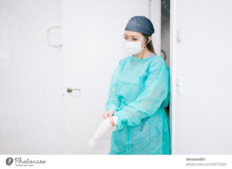 Zahnarzt, der einen Schutzanzug trägt und Handschuhe anzieht Job Berufe Berufstätigkeit Beschäftigung Jobs Brillen Arbeit hoeren Gesundheit Gesundheitswesen